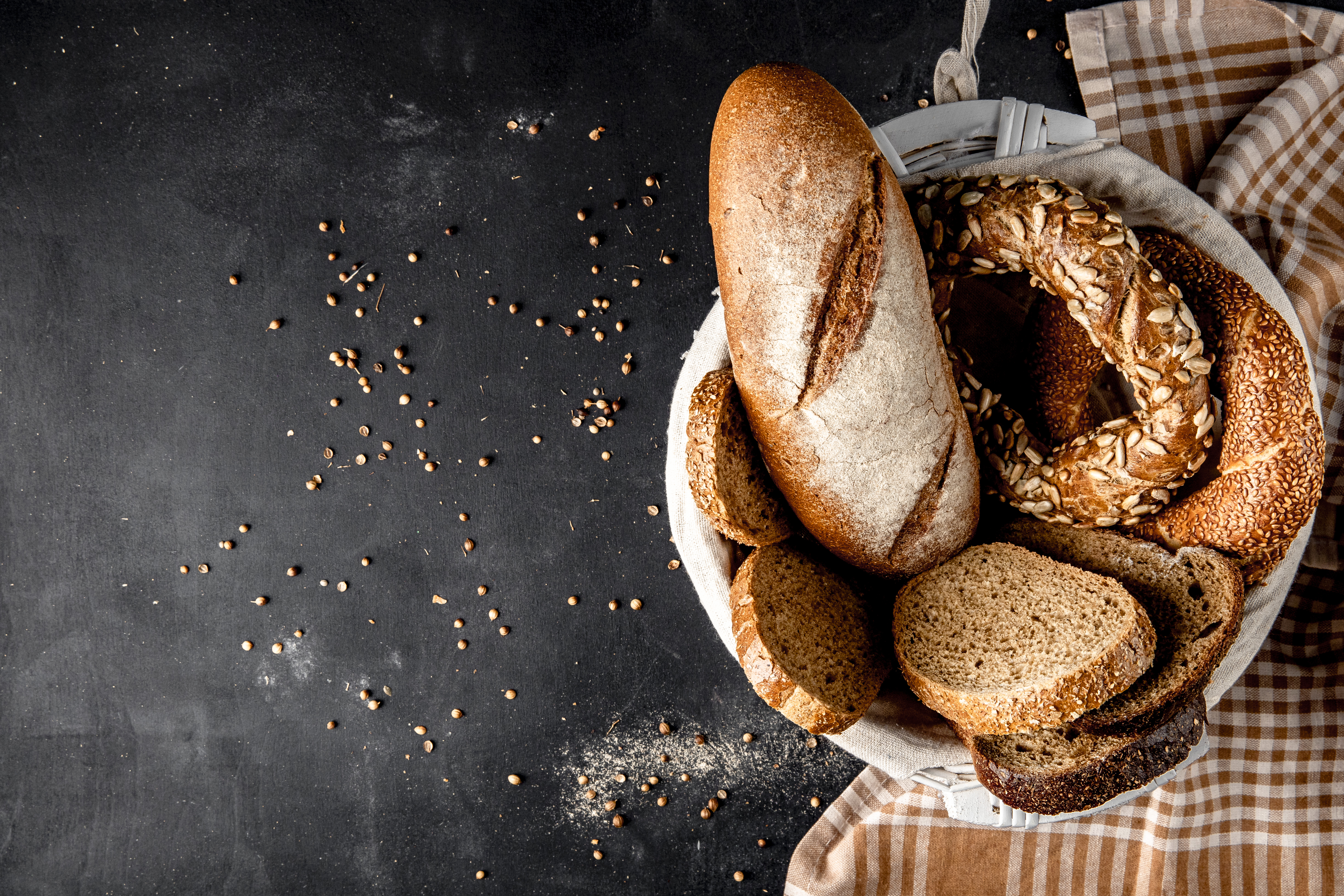 top-view-basket-full-breads-as-baguette-bagel-rye-with-sunflower-seeds-black-surface.jpg