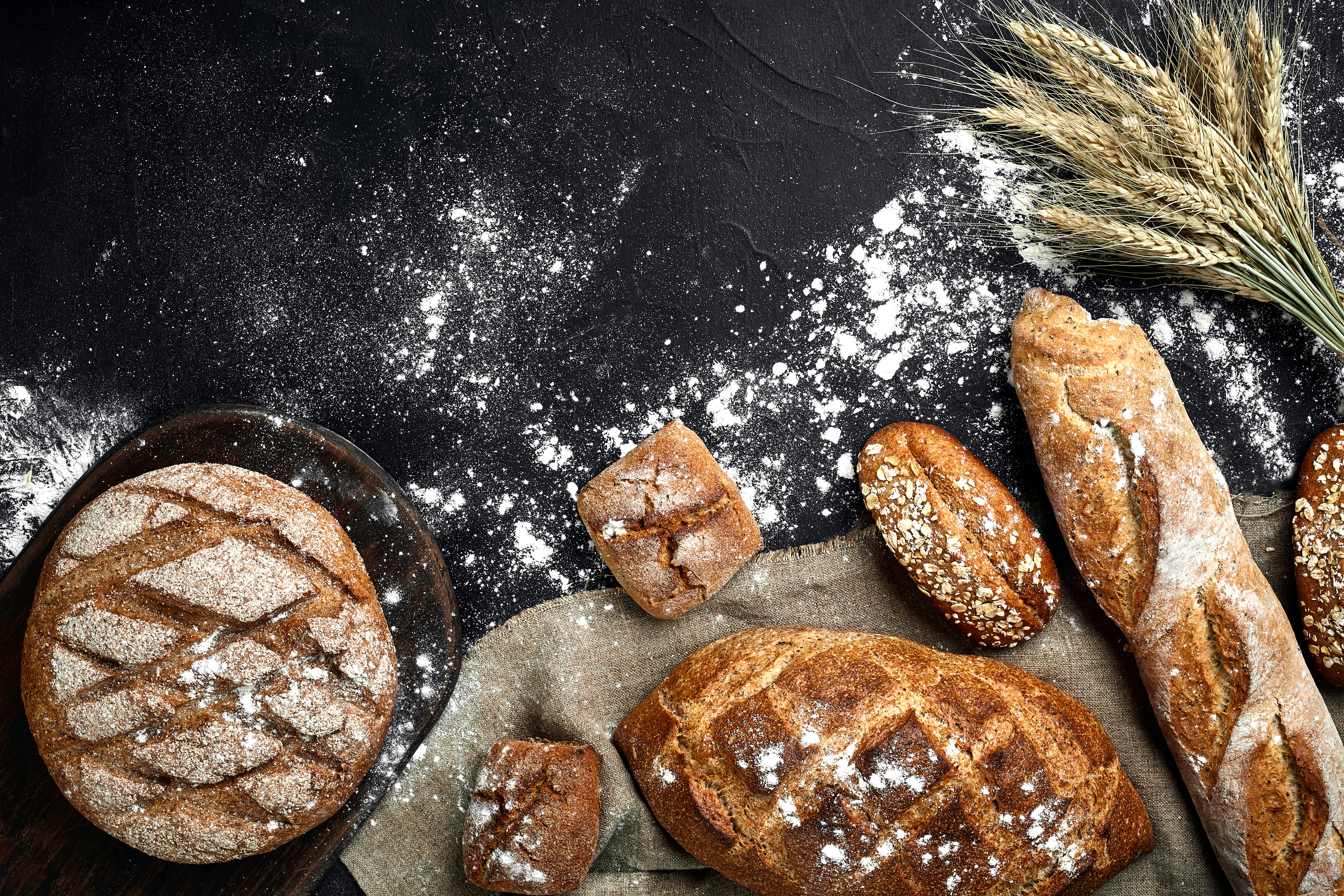 homemade-rye-bread-sprinkled-with-flour-various-grains-seeds-black-background-with-spikelets-wheat-rye-oats.jpg