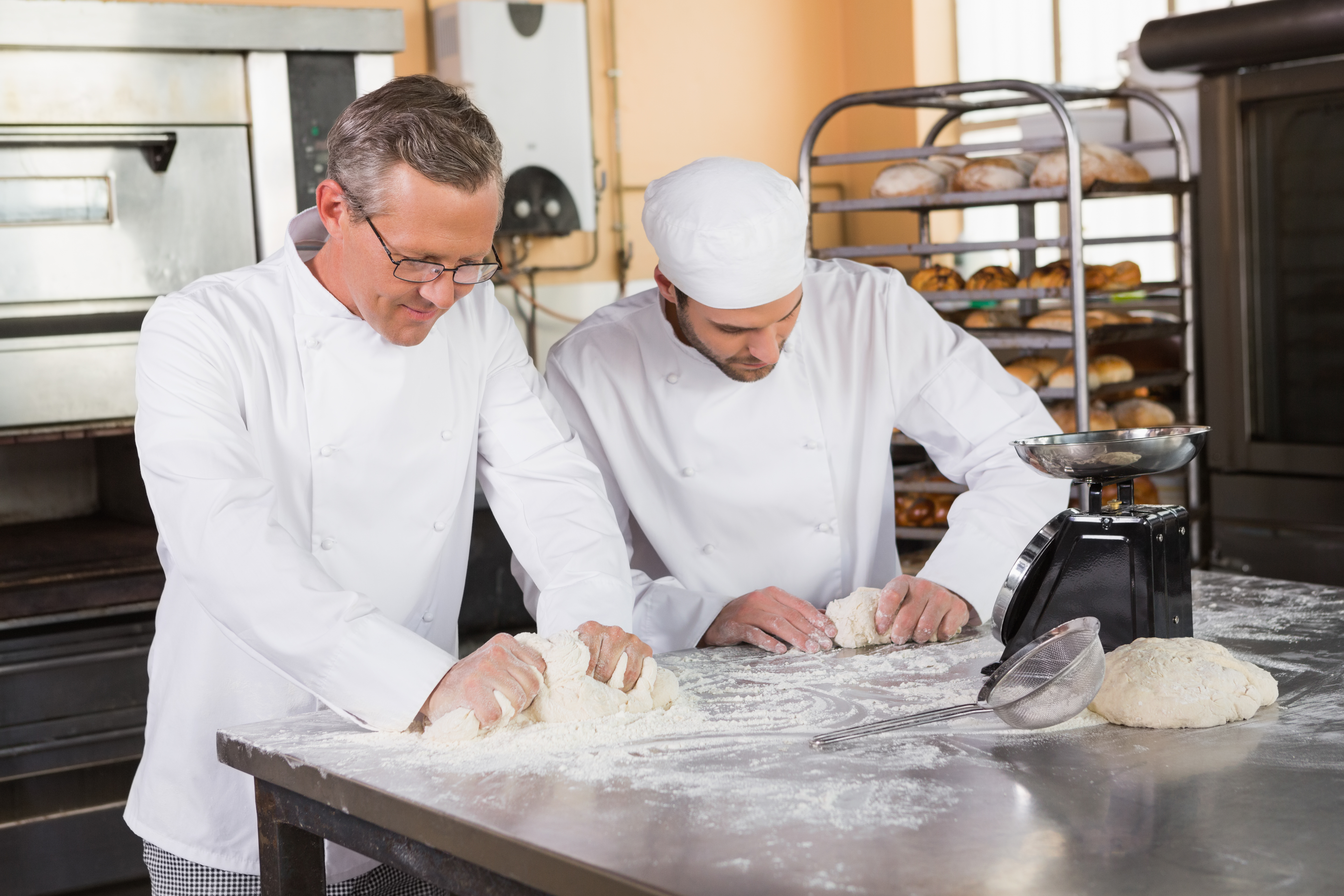 focused-bakers-kneading-dough-counter.jpg